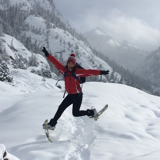 Cindy snowshoeing in the mountains, arms out and laughing